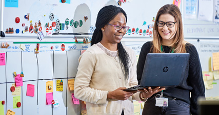 Two staff members smile at a laptop screen during a meeting