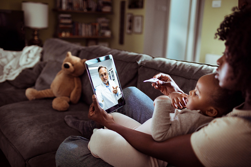 Mother and child lying on sofa undergoing online consultation on ipad